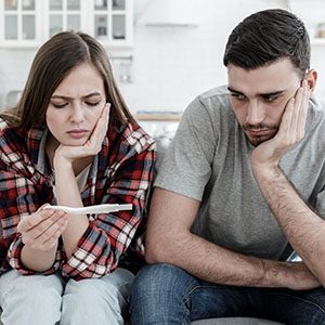 Young couple worried because of positive result of ovulation test, looking upset and bewildered